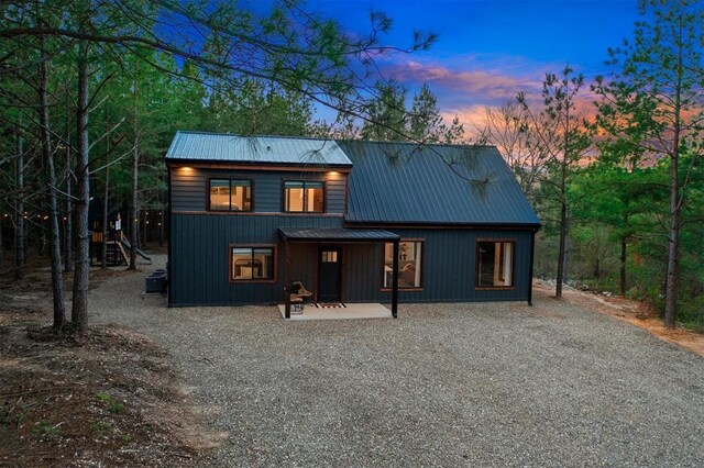 back house at dusk with central air condition unit and a patio area