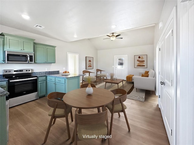 kitchen with dark wood-type flooring, stainless steel appliances, vaulted ceiling, and green cabinets