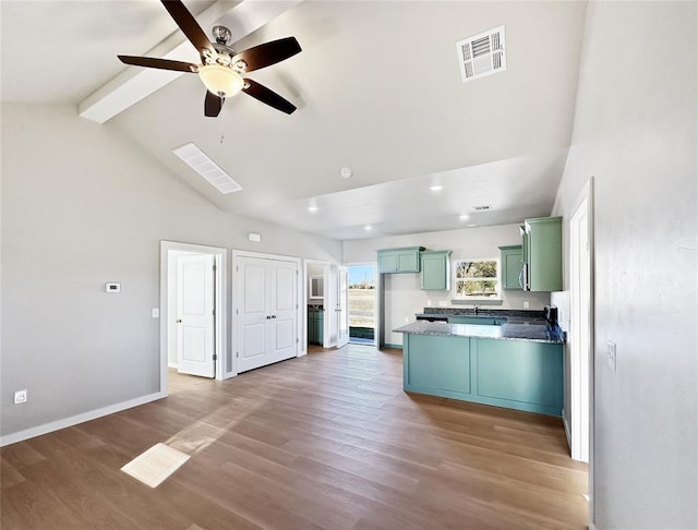 kitchen featuring ceiling fan, wood-type flooring, and vaulted ceiling with beams