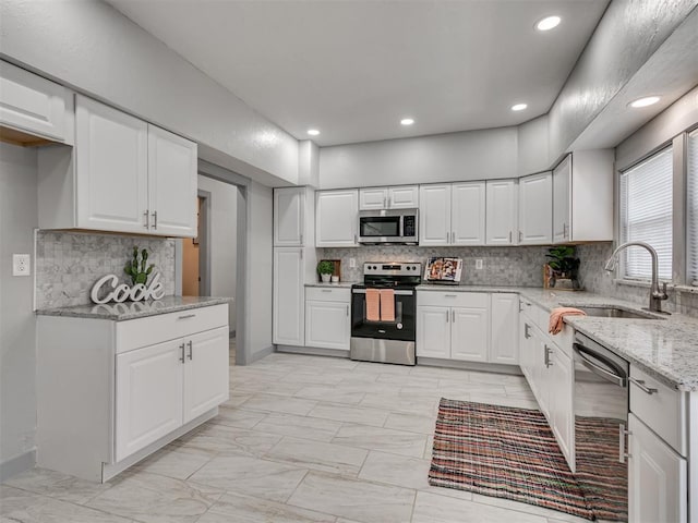 kitchen featuring light stone counters, appliances with stainless steel finishes, sink, and white cabinets