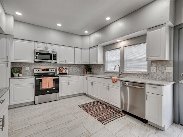 kitchen featuring stainless steel appliances, white cabinetry, sink, and backsplash