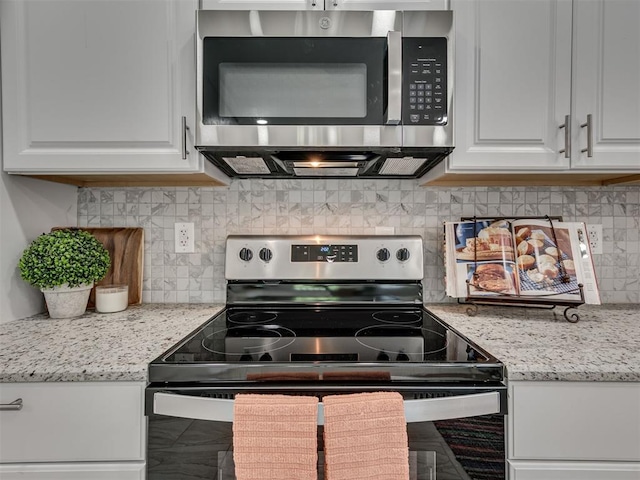 kitchen featuring light stone countertops, decorative backsplash, stainless steel appliances, and white cabinets