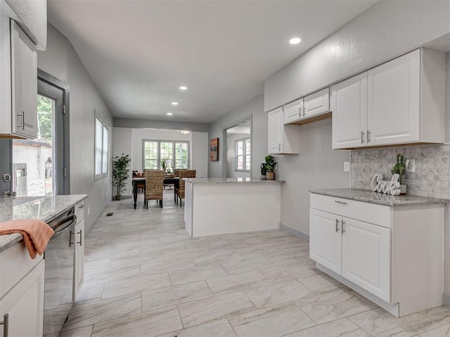 kitchen with dishwashing machine, decorative backsplash, light stone countertops, and white cabinets