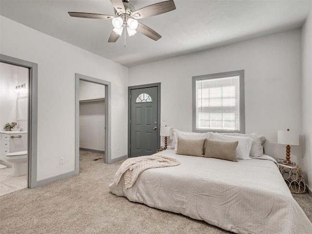 bedroom featuring a spacious closet, light colored carpet, ceiling fan, ensuite bath, and a closet