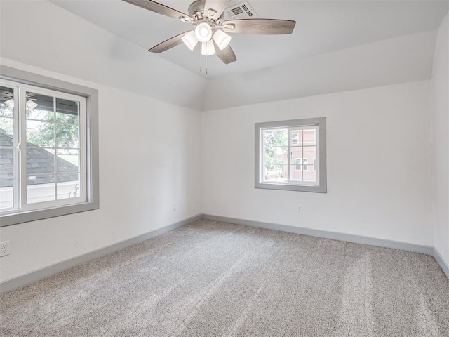 spare room with ceiling fan, carpet floors, vaulted ceiling, and a wealth of natural light