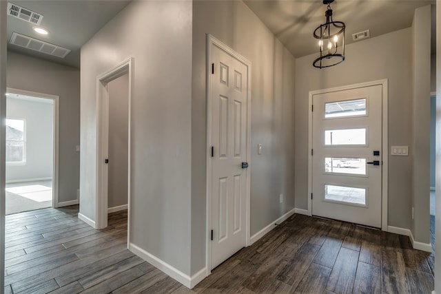 entrance foyer with dark hardwood / wood-style floors and an inviting chandelier