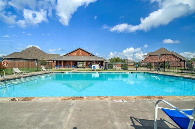 pool with a patio and fence