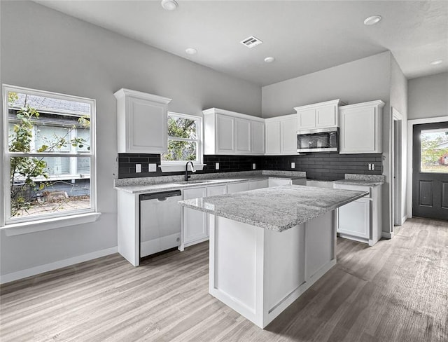 kitchen featuring appliances with stainless steel finishes, white cabinets, decorative backsplash, a center island, and light hardwood / wood-style flooring