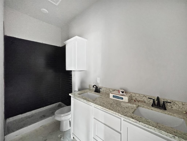 bathroom with vanity, tiled shower, and toilet