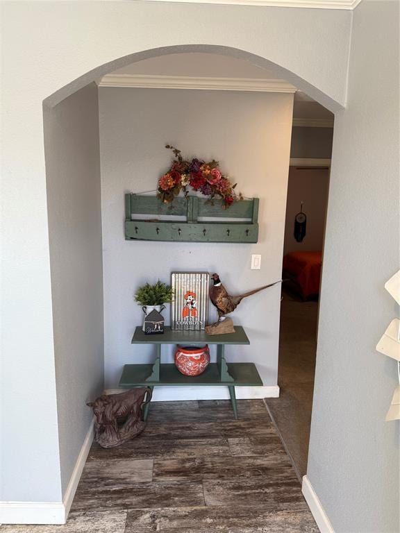hall with arched walkways, crown molding, wood finished floors, and baseboards