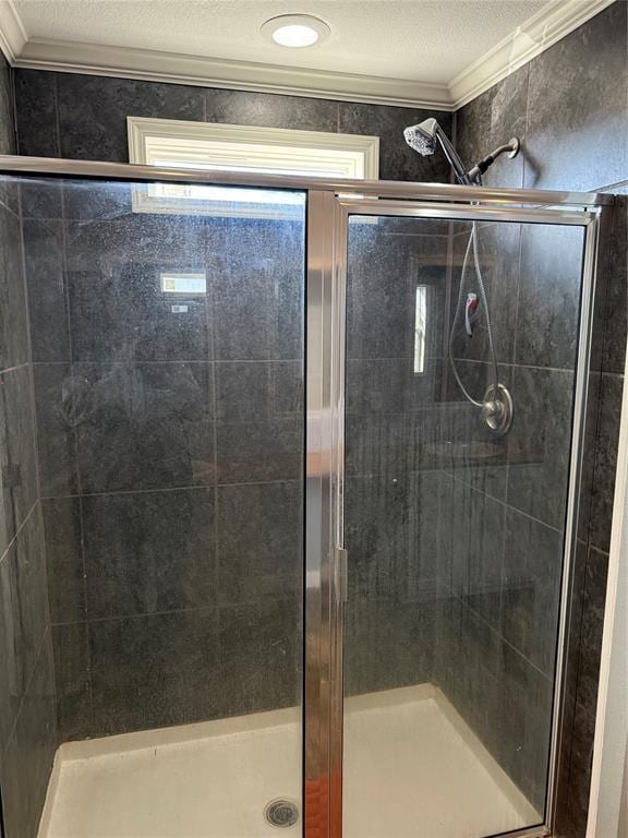 full bath featuring a textured ceiling, a stall shower, and ornamental molding