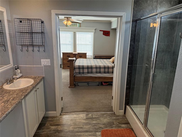 ensuite bathroom featuring ensuite bathroom, wood finished floors, a shower stall, and a ceiling fan