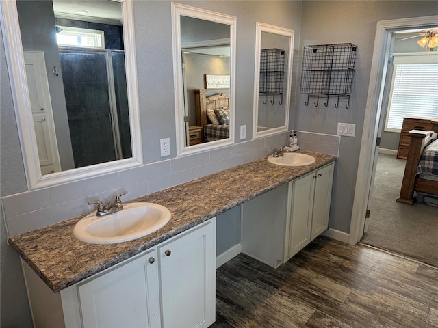 ensuite bathroom with wood finished floors, ensuite bath, a sink, and double vanity