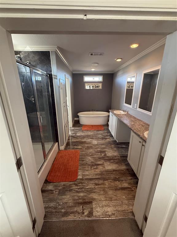 bathroom featuring a shower stall, wood finished floors, visible vents, vanity, and crown molding