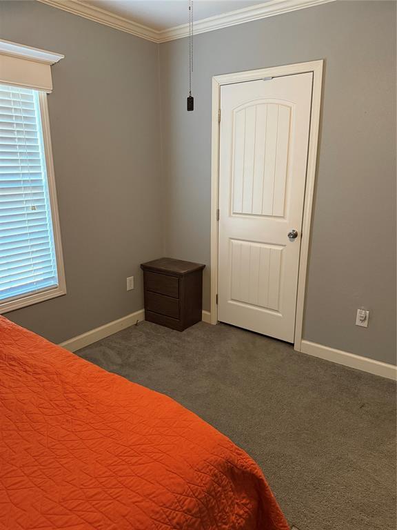 unfurnished bedroom with baseboards, crown molding, and dark colored carpet