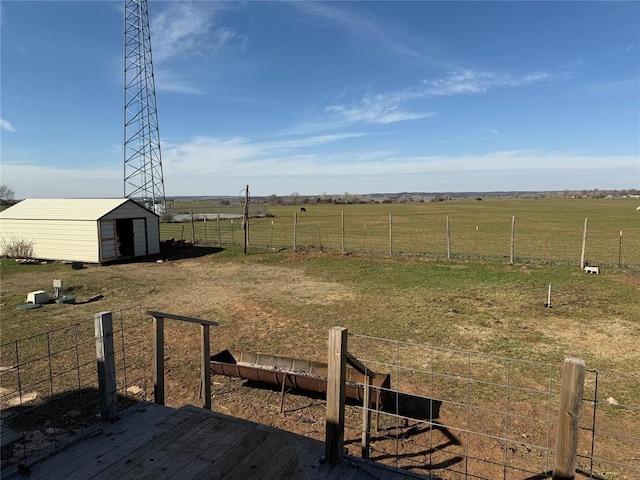 view of yard featuring a rural view, fence, an outbuilding, a wooden deck, and a storage unit