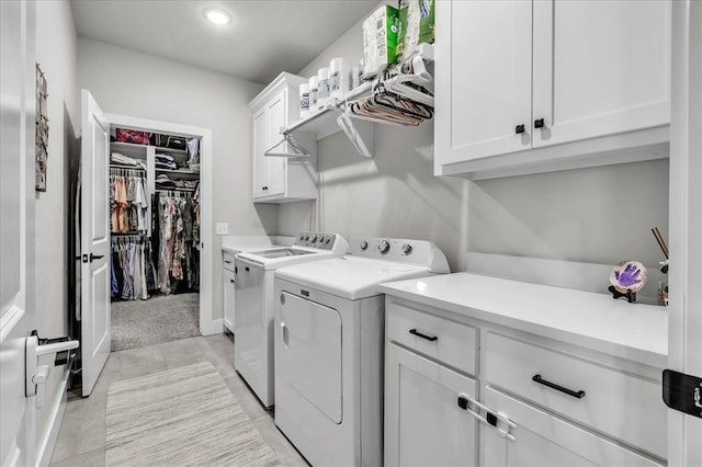 laundry area featuring cabinets, light tile patterned floors, and washer and clothes dryer