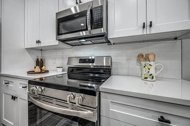 kitchen with decorative backsplash, white cabinets, and appliances with stainless steel finishes