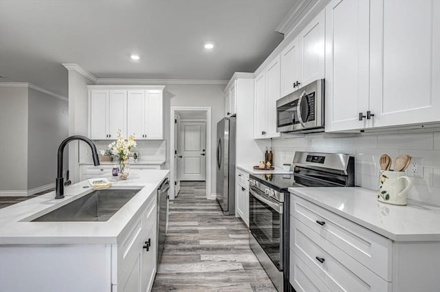 kitchen featuring ornamental molding, appliances with stainless steel finishes, sink, and white cabinets