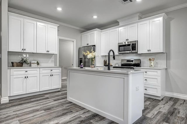 kitchen with a kitchen island with sink, crown molding, white cabinets, and appliances with stainless steel finishes