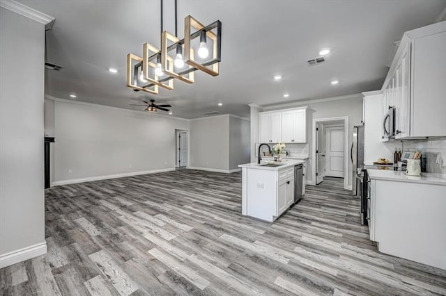 kitchen featuring pendant lighting, ceiling fan, stainless steel appliances, ornamental molding, and white cabinets