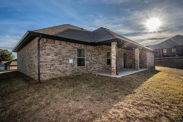 back of property featuring a lawn and a patio