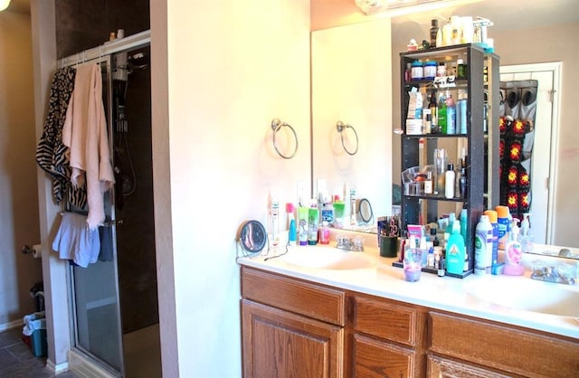 full bath with a sink, double vanity, and a shower stall