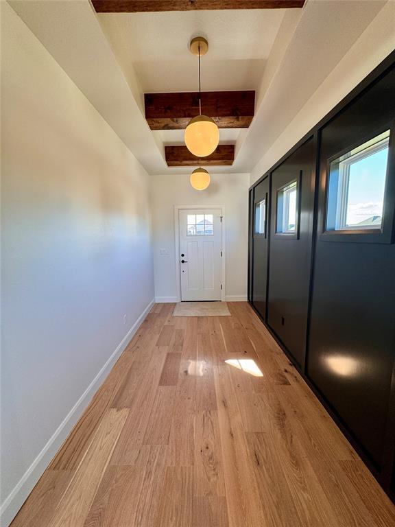 12812 Cobblestone Curve Rd, Oklahoma City, OK 73142 - doorway featuring light wood-type flooring, baseboards, beam ceiling, and a tray ceiling
