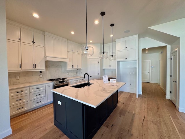 12812 Cobblestone Curve Rd, Oklahoma City, OK 73142 - kitchen with a sink, an island with sink, light wood-type flooring, white cabinets, and backsplash