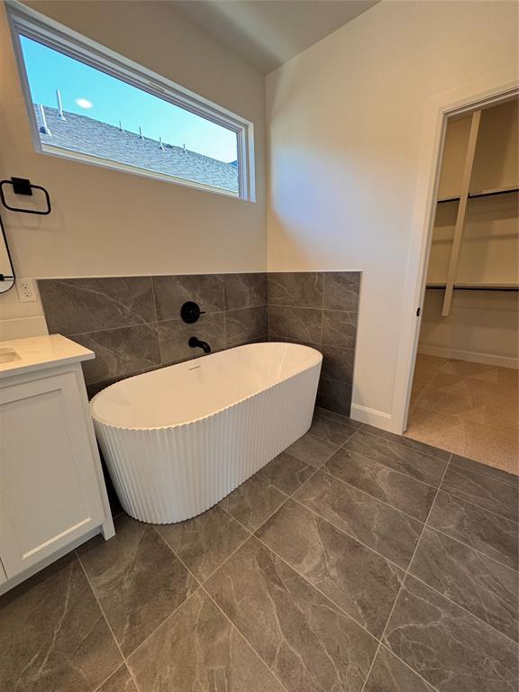 12812 Cobblestone Curve Rd, Oklahoma City, OK 73142 - bathroom with tile walls, wainscoting, vanity, and a freestanding bath