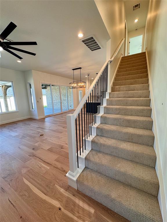 12812 Cobblestone Curve Rd, Oklahoma City, OK 73142 - stairway with visible vents, baseboards, wood finished floors, and ceiling fan with notable chandelier