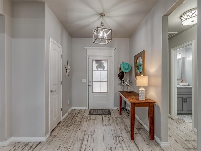 foyer with baseboards, a notable chandelier, and light wood-style floors