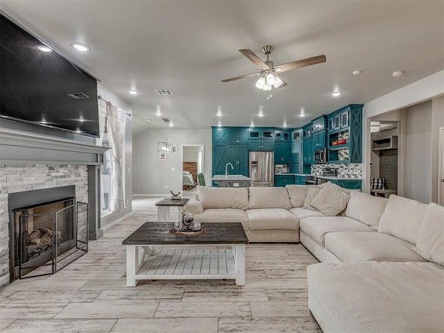 living area with recessed lighting, ceiling fan, visible vents, and a stone fireplace