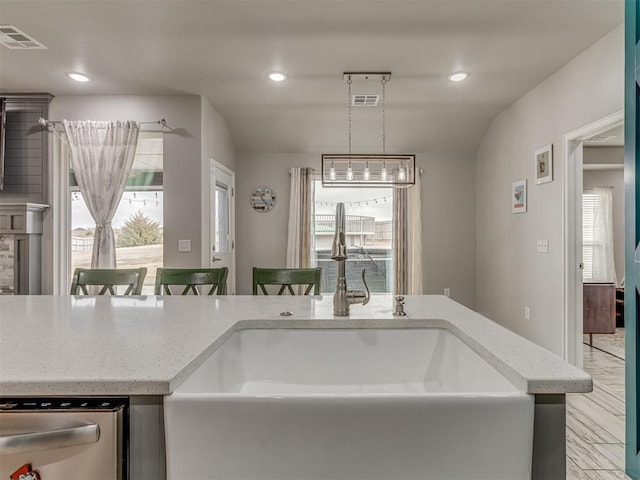 kitchen with decorative light fixtures, visible vents, stainless steel dishwasher, a sink, and a kitchen bar