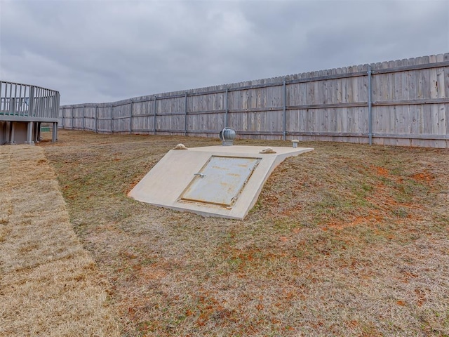 view of storm shelter with a fenced backyard and a yard