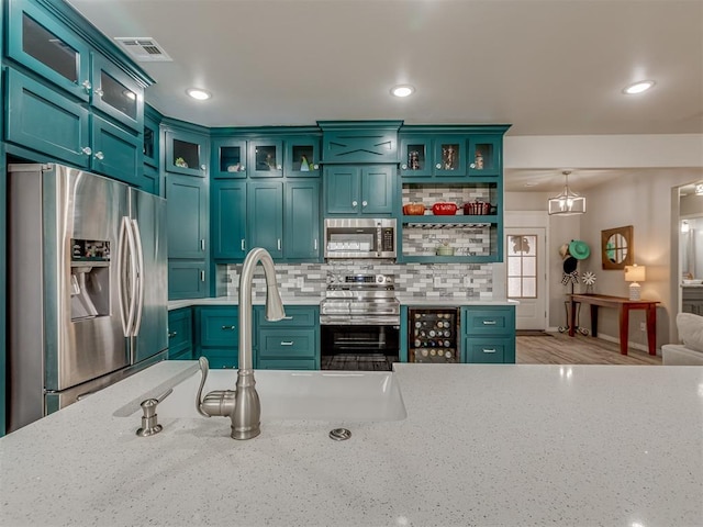 kitchen with decorative light fixtures, stainless steel appliances, visible vents, backsplash, and glass insert cabinets