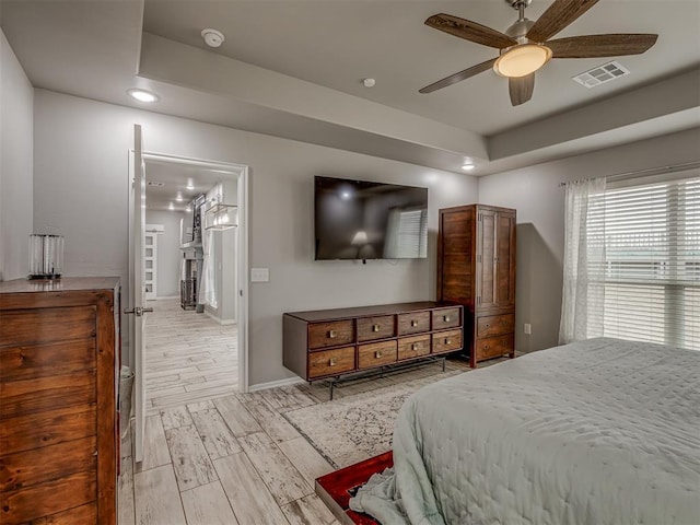 bedroom featuring baseboards, a tray ceiling, visible vents, and wood tiled floor