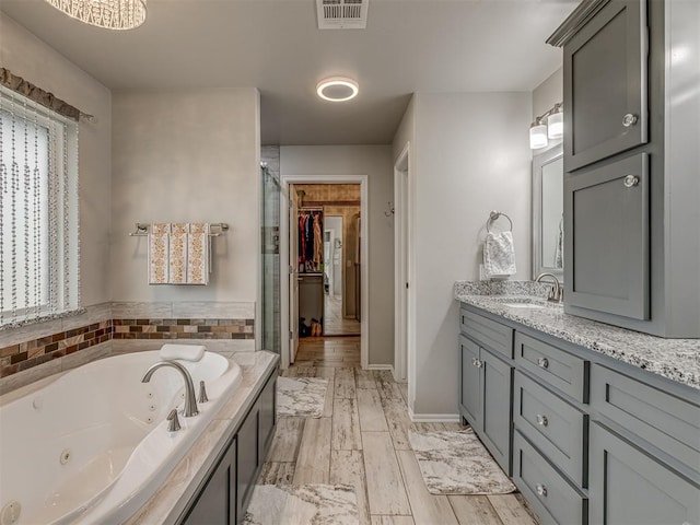 full bath featuring visible vents, wood tiled floor, a shower stall, vanity, and a tub with jets