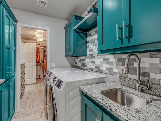 laundry room with cabinet space, visible vents, a sink, separate washer and dryer, and light wood-type flooring