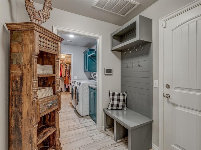 mudroom with washing machine and dryer, visible vents, and wood finish floors