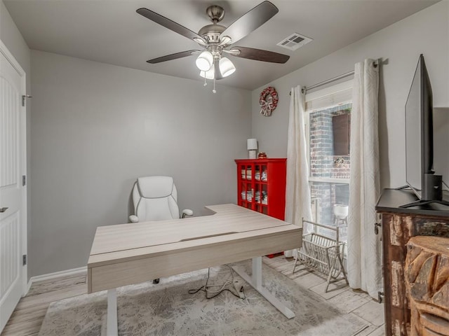 home office with a ceiling fan, baseboards, visible vents, and light wood finished floors