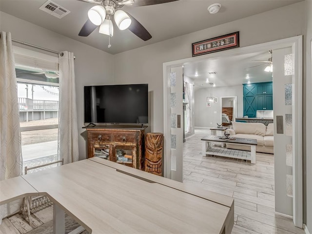 living area featuring light wood finished floors, visible vents, and a ceiling fan