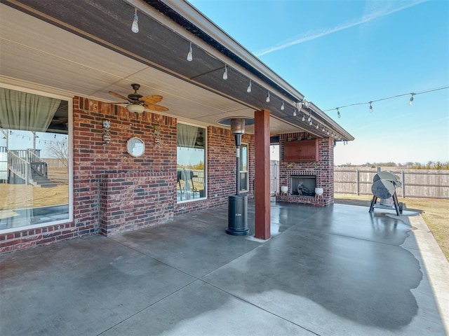 view of patio / terrace with an outdoor brick fireplace, fence, and a ceiling fan