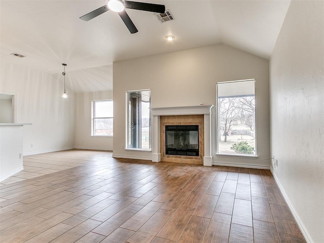 unfurnished living room with lofted ceiling, ceiling fan, visible vents, and a tiled fireplace