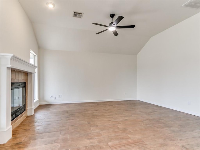 unfurnished living room with vaulted ceiling, ceiling fan, a tiled fireplace, and visible vents