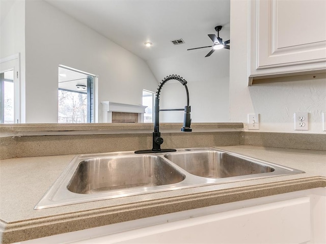 interior details featuring a fireplace, light countertops, visible vents, white cabinets, and a sink