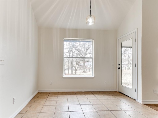 empty room featuring lofted ceiling, baseboards, and light tile patterned floors