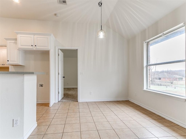 unfurnished dining area with light tile patterned floors, visible vents, baseboards, and a wealth of natural light