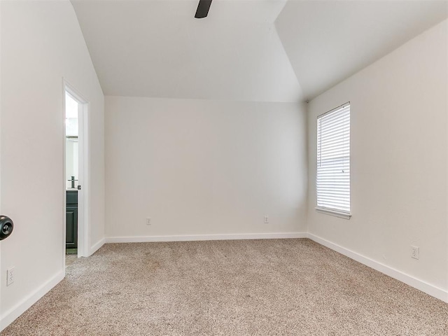 spare room with vaulted ceiling, ceiling fan, baseboards, and light colored carpet