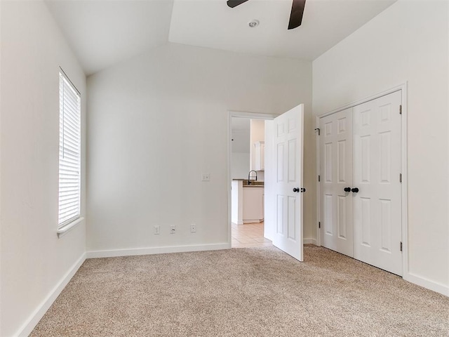 unfurnished bedroom featuring light carpet, baseboards, a sink, and lofted ceiling